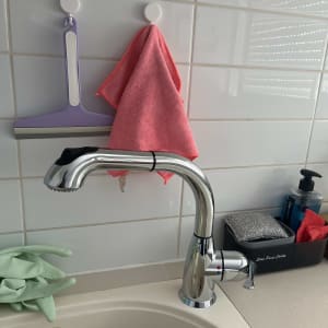 ברז מטבח עם כפפות גומי ירוקות וסבון כלים