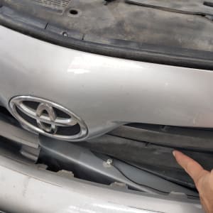 יד מצביעה על פגוש קדמי של רכב עם סמל טויוטה