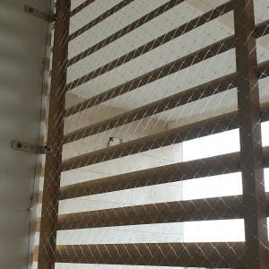 רשת מתוחה על תריסי עץ למניעת כניסת יונים