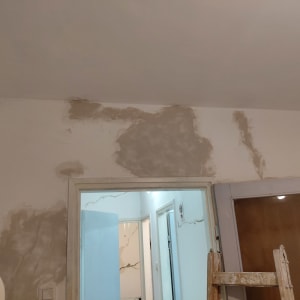 קיר עם תיקוני טיח וסולם עץ