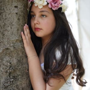 נערה עם זר פרחים על ראשה ליד עץ