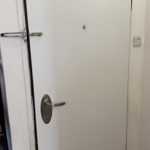 דלת לבנה עם ידית מתכת ובריח ביטחון