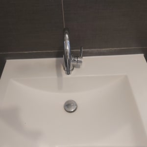 כיור עם ברז כרום על רקע קיר אריחים אפור