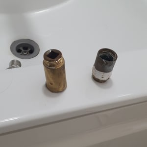 שני מחברים מתכתיים על שפת כיור לבן