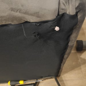 מברג מונח על רצפה ליד כיסא עם קרעים בבד