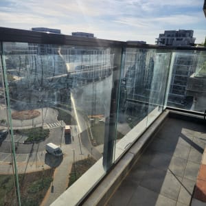 מעקה זכוכית במרפסת עם נוף עירוני