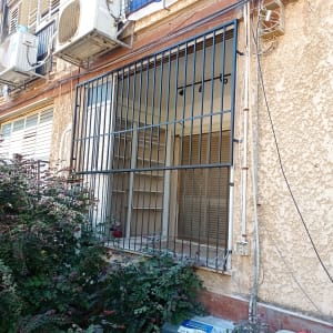 סורגים מותקנים על חלון בניין עם מזגנים