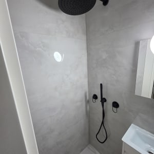 מקלחת עם ראש מקלחת שחור וקיר אריחים אפור