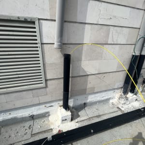 צינור פלסטיק עם כבל צהוב על קיר חיצוני