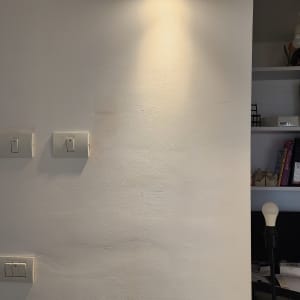 מנורת קיר דולקת ומתגי חשמל על הקיר