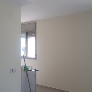 קיר צבוע בצבע בהיר עם חלון ומקל צבע