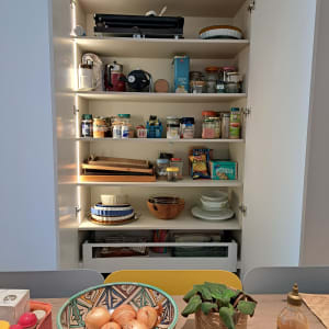 ארון מטבח פתוח עם מדפים מלאים בצנצנות ותבלינים