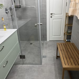 חדר אמבטיה עם מקלחון, כיור, ומדף עץ.