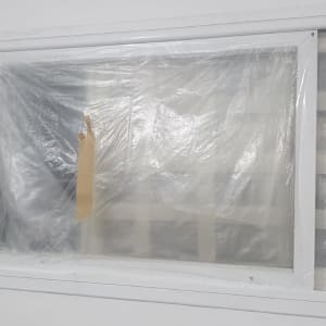 חלון מכוסה בניילון שקוף עם סרט דבק