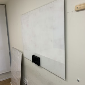 לוח זכוכית תלוי על קיר עם מחזיק שחור