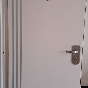 דלת לבנה עם ידית מתכת ועיטורים אנכיים