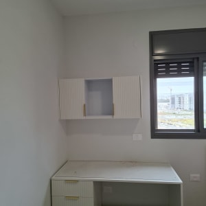 שולחן עבודה עם ארונות ומגירות ליד חלון