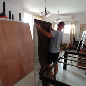 אדם מזיז דלת עץ בחדר עם רהיטים ארוזים