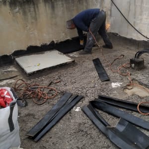 אדם עובד על איטום גג עם יריעות ביטומניות.