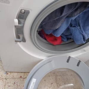מכונת כביסה עם דלת זכוכית שבורה שמנותקת מהציר