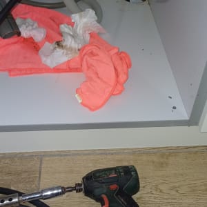 כלי עבודה וצינורות מתחת לכיור, מגבת נייר ופלסטיק