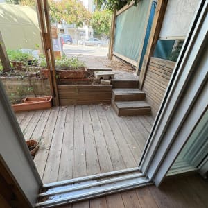 מרפסת עץ עם עציצים ומדרגות עץ קטנות.