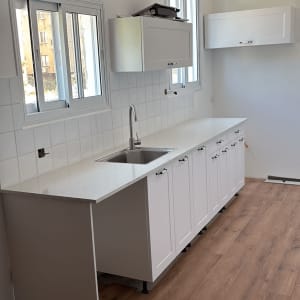 מטבח חדש עם ארונות לבנים ומשטח עבודה מעץ