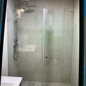 מקלחון זכוכית חזיתי מותקן בחדר רחצה מרוצף עם מוט פינוק