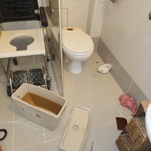 אסלה מפורקת עם מיכל מים וכלי עבודה על הרצפה