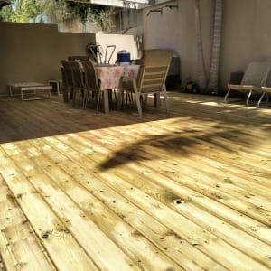 דק עץ עם שולחן וכיסאות בגינה