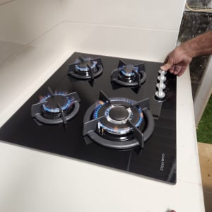 כיריים גז עם ארבעה מבערים דולקים, יד מסובבת כפתור