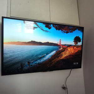 טלוויזיה תלויה על הקיר עם כבל חשמל גלוי