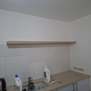 מדף עץ מותקן מעל כיור במטבח עם חומרי ניקוי