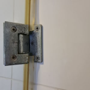 ציר מתכת לדלת מקלחון על קיר אריחים