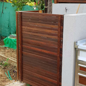 שער עץ חום ליד קיר בטון בגינה