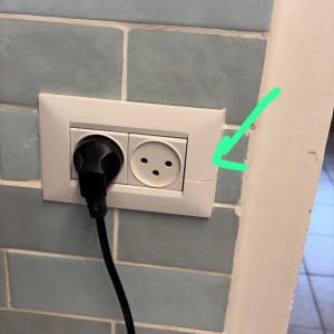 שקע חשמלי עם תקע מחובר על קיר מרוצף