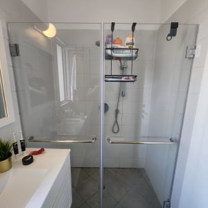 מקלחת עם דלתות זכוכית, מדף עם מוצרי רחצה