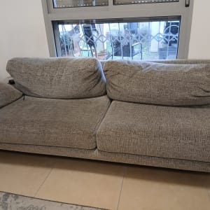 ספה אפורה ליד חלון עם סורגי מתכת