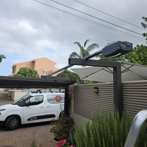 שער חשמלי עם מנוע ומכונית לבנה ברקע