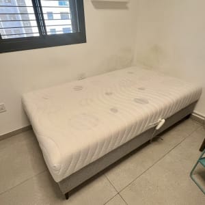 מיטה בחדר עם חלון וארון קטן