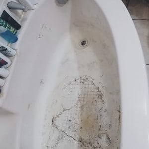 אמבטיה ישנה עם סדקים ולכלוך, זקוקה לשיפוץ