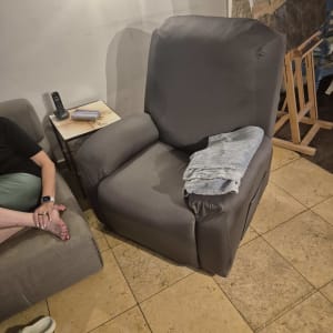 כורסה אפורה בחדר עם מנורה ושולחן קטן
