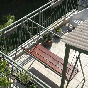 ספסל עץ תלוי על מתקן מתכת במרפסת