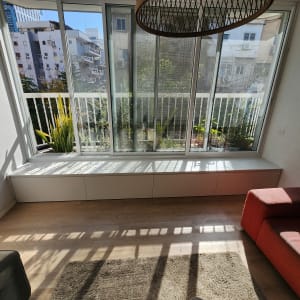 חלון גדול עם אדן מעץ וצמחייה בחוץ