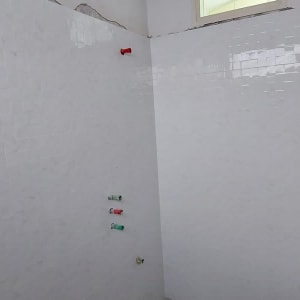 קיר עם אריחים לבנים וצינורות חשופים