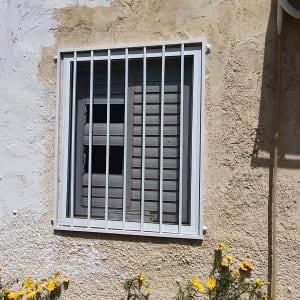 חלון עם סורגים לבנים על קיר חיצוני