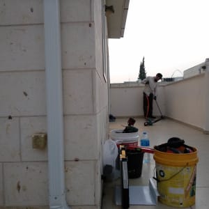 אדם מנקה גג עם דלי וכלים שונים