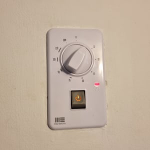 תרמוסטט עם כפתור הפעלה על קיר