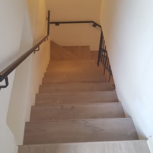 מדרגות עץ עם פרקט בהיר ומעקה מתכת