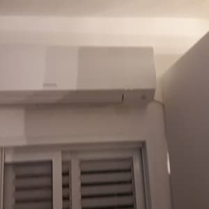 מזגן קיר לבן מותקן מעל חלון